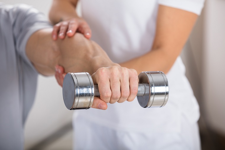 Physiotherapist Helping Man To Exercise